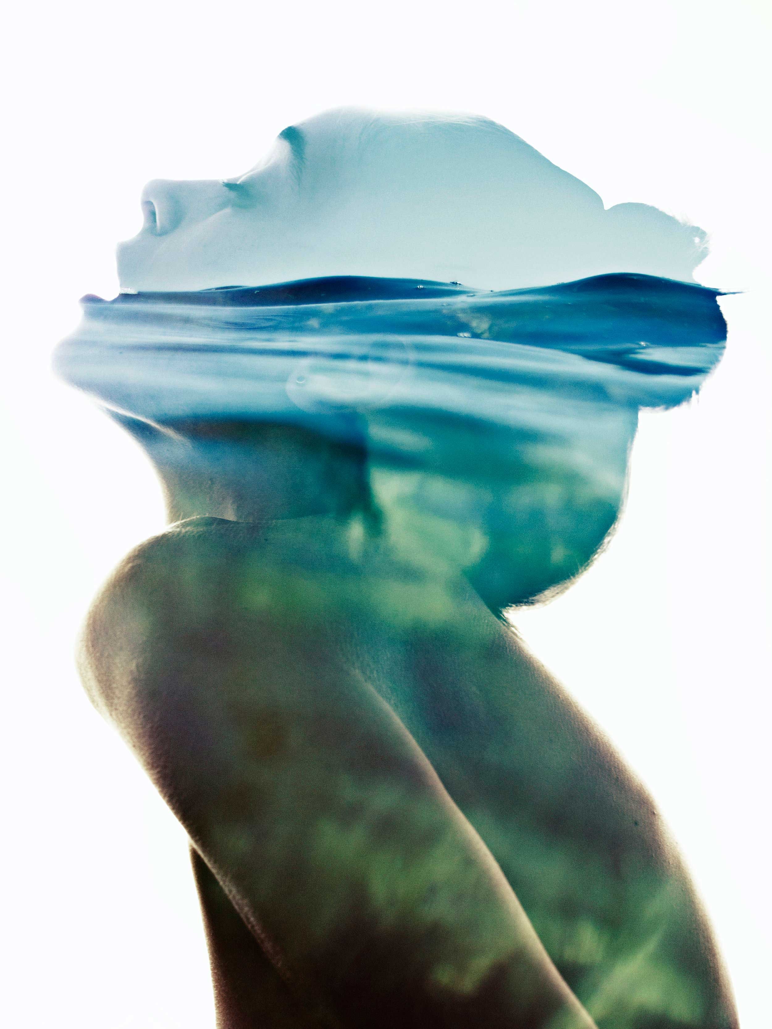 A double exposure photograph combining a woman's profile with water, creating an artistic effect of water blending into her face and body.