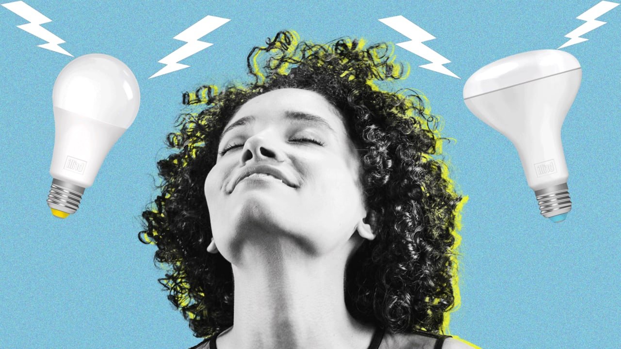 A woman with curly hair smiling with closed eyes, with two light bulbs emitting lightning bolts around her head.