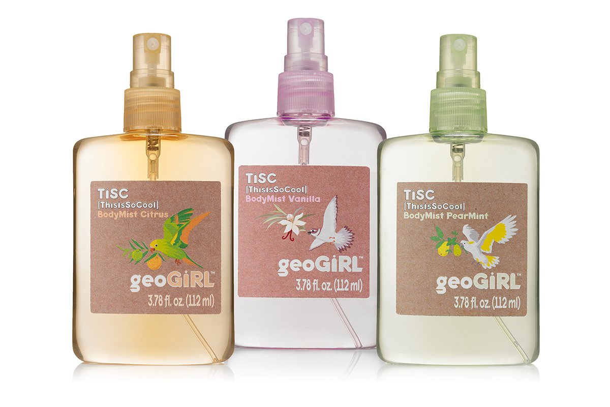 Three bottles of geoGIRL body mist with produce and bird illustrations on the labels, arranged in a row, with citrus, vanilla, and pear mint scents.