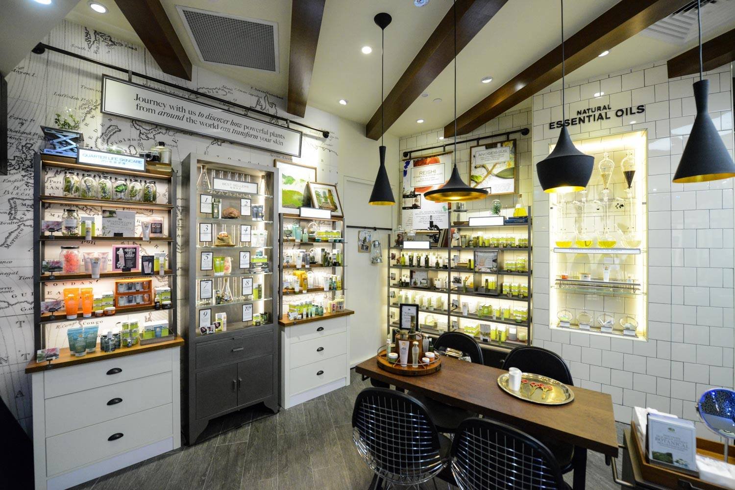 Interior of a natural skincare store with shelves of products, a table with samples, and hanging pendant lights.