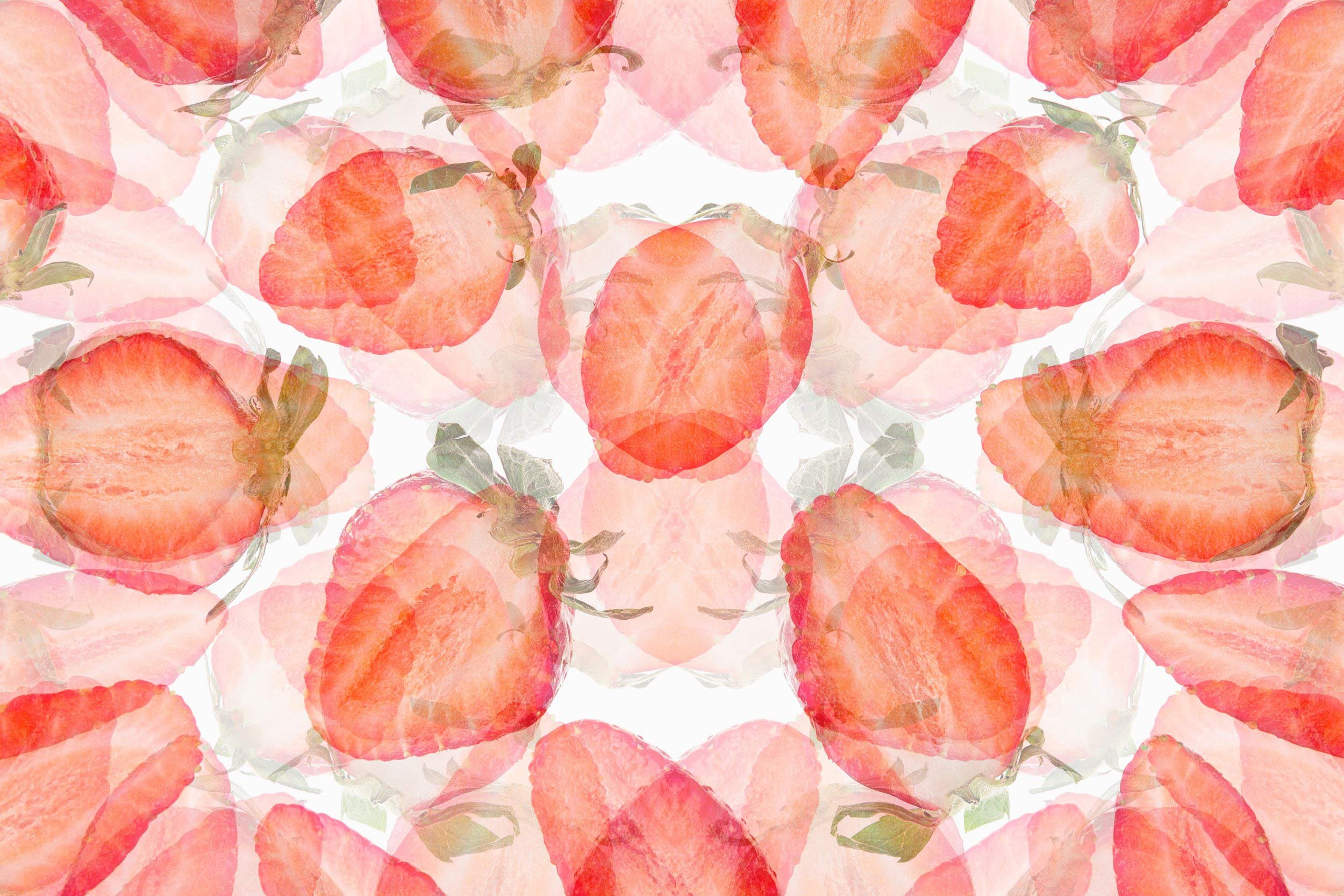 Pattern of sliced strawberries with green leaves in a kaleidoscopic arrangement.